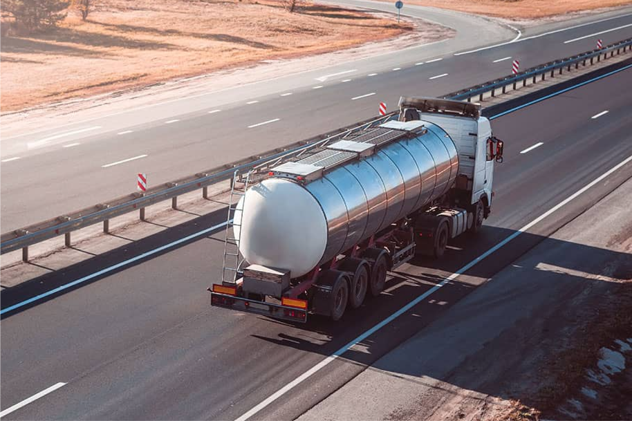 Tankbil i trafikk på hovedvei som illustrerer effektiv ruteplanlegging for presis henting og levering av flytende gods.